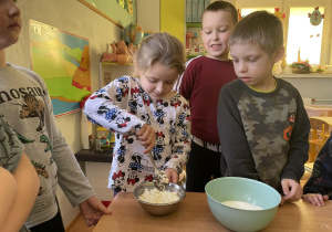Dziewczynka dodaje składniki do ciasta