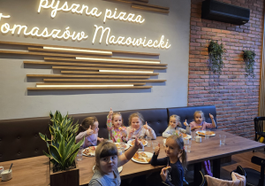 Dzieci jedzą wykonaną przez siebie pizzę