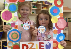 Dwie dziewczynki pozują do zdjęcia trzymając fotoramkę z napisem „Dzień Kropki”