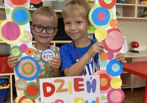 Dwóch chłopców pozują do zdjęcia trzymając medale i fotoramkę z napisem „Dzień Kropki”