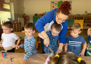 Chłopiec nasypuję ziemie do doniczki