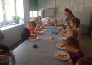 Dzieci jedzą sałatkę owocową.