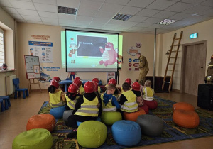 Dzieci w strojach strażackich oglądają film edukacyjny