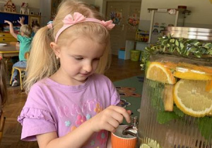 Dziewczynka nalewa sobie lemoniadę zrobioną przez dzieci