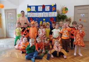 Dzieci wraz z nauczycielką pozują do zdjęcia na balu jesieni