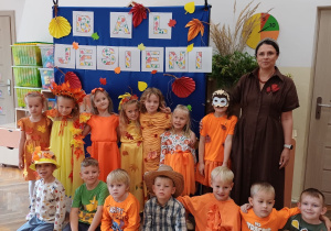 Dzieci wraz z nauczycielką pozują do zdjęcia na balu jesieni