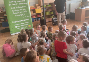Dzieci siedzą na dywanie i słuchają koncertu