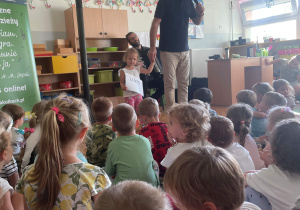 Dzieci siedzą na dywanie i słuchają koncertu muzycznego