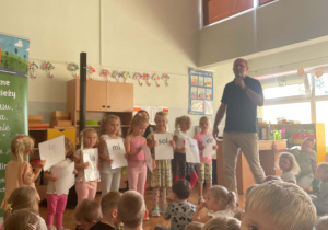 Dzieci siedzą na dywanie i słuchają koncertu muzycznego