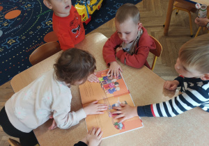 Dzieci z grupy Odkrywcy rozmawiają o emocjach oglądając książkę