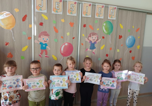 Dzieci pozują do zdjęcia z kolorowankami z okazji Światowego Dnia Zwierząt