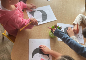 Dzieci siedzą i wykonują karty pracy związane z Dniem Uśmiechu