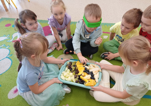 Chłopiec z zasłoniętymi oczami próbuje owoców