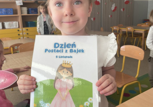 Dziewczynka trzyma plakat z okazji Dnia Postaci z Bajek