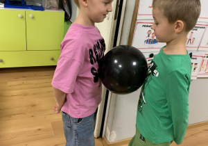 Chłopcy trzymają balon brzuchami