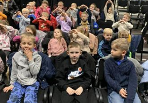 Dzieci siedzą w sali teatralnej