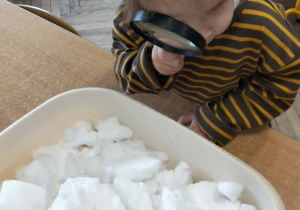 Dziewczynka ogląda lupą śnieg