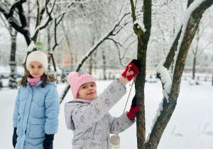 Dziewczynki wieszają pokarm dla ptaków
