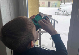 Chłopiec wypatruje ptaków przez lornetkę
