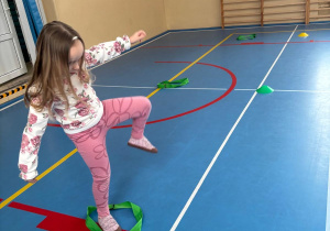 Dziewczynka bierze udział w zawodach sportowych skacząc do szarfy