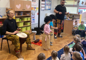 Dzieci ubrane w specjalne stroje tańczą i grają na instrumentach