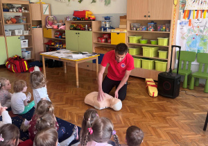 Ratownik pokazuje na manekinie jak robić sztuczne oddychanie