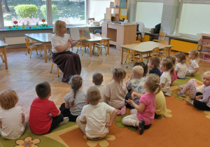 Dzieci słuchają bajki, którą czyta nauczycielka