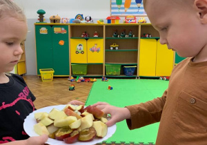 Chłopiec częstuje się owocami