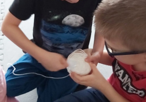 Przedszkolaki pocierają plastikową łyżeczkę o wełnę