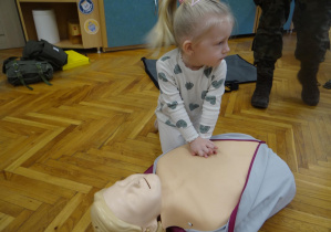 Dziewczynka pokazuje jak udzielać pierwszej pomocy