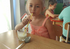 Dziewczynka pije mleko przez słomkę