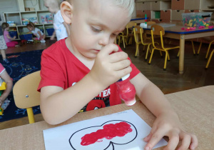 Chłopiec maluje jabłko