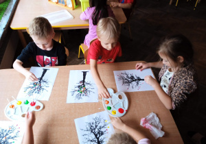 Przedszkolaki malują drzewo farbami