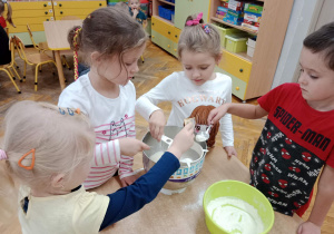 Przedszkolaki przesiewają mąkę do ciasta