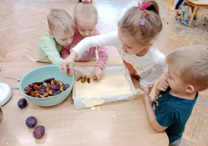 Dzieci ozdabiają ciasto śliwkami