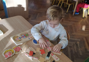Chłopiec układa drewniane puzzle