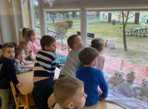 Dzieci obserwują ptaki w ogrodzie przedszkolnym