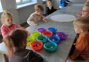 Dzieci tworzą pracę plastyczną z guzików
