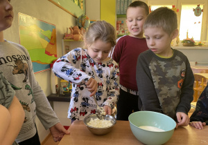 Dziewczynka dodaje składniki do ciasta