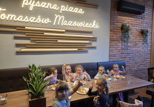 Dzieci jedzą wykonaną przez siebie pizzę