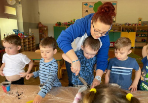 Chłopiec nasypuję ziemie do doniczki