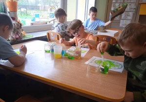 Dzieci za pomocą pipet i wody tworzą obrazki