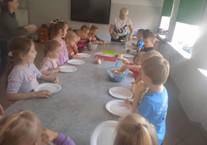 Dzieci jedzą sałatkę owocową.