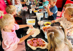 Dzieci biorą udział w warsztatach z robienia pizzy