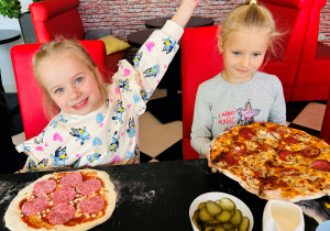 Dziewczynki pozują do zdjęcia z własnoręcznie przygotowanymi pizzami