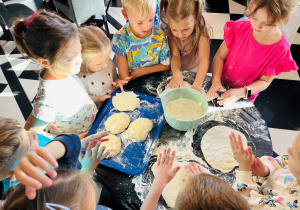 Dzieci ugniatają pizzę podczas warsztatów kulinarnych