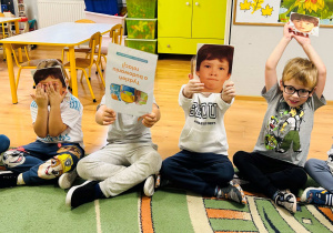 Dzieci siedzą na dywanie i pokazują emocje