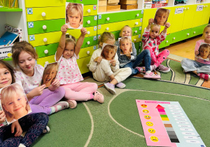 Dzieci siedzą na dywanie i pokazują emocje