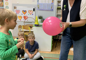 Nauczycielka trzyma balon a chłopiec go przebija