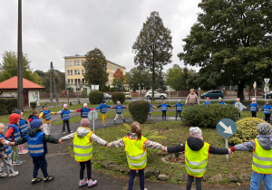 Dzieci bawią się ubrane w kamizelki odblaskowe z okazji Dnia Odblasku